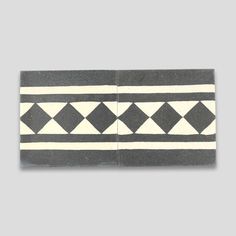 two pieces of black and white tile with geometric designs on the bottom, one in grey and