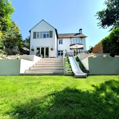 a large white house with a slide in the front yard and grass area around it