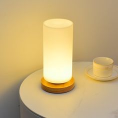 a white table with a light on it next to a cup