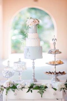 a table topped with a white cake covered in frosting next to other desserts