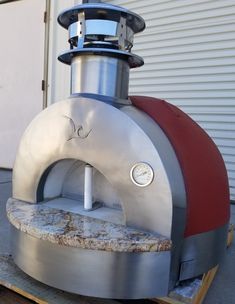 an outdoor pizza oven sitting on top of a pallet next to a garage door