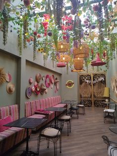 a restaurant with tables and chairs covered in hanging plants on the walls, along with wicker baskets filled with flowers