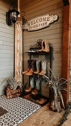 a welcome to our farm sign hanging on the side of a building with boots and plants