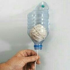 a hand holding a ball of yarn on top of a string attached to a water bottle