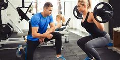 a man and woman doing squats in a gym