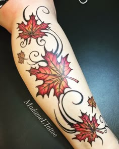 a woman's leg with red leaves and swirls on the bottom half of it