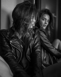 two women in leather jackets sitting on a couch