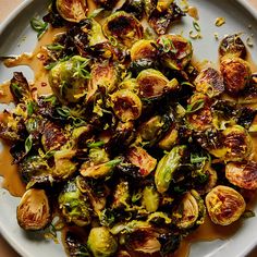 a white plate topped with brussel sprouts covered in sauce and seasoning