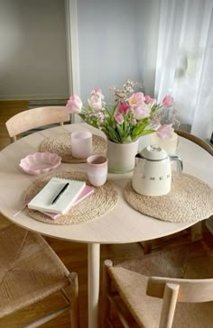 the table is set with pink flowers in vases and books on it, along with two chairs