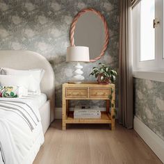 a white bed sitting next to a wooden table with a mirror on top of it