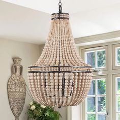 a wooden beaded chandelier hanging from a ceiling in a room with windows