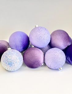 purple and silver ornaments are stacked on top of each other in the shape of balls