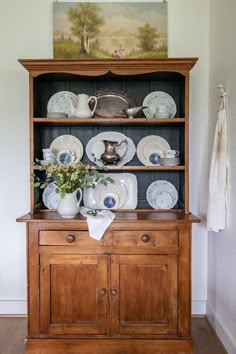 an old wooden china cabinet with dishes on it