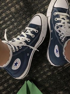 a pair of blue converse shoes sitting on top of a carpet