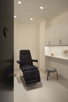 a black reclining chair sitting in the middle of a room with white walls and cabinets