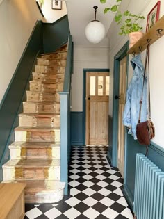 a hallway with black and white checkered flooring, blue walls and wooden stairs