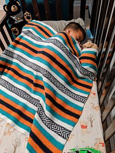 a small child sleeping in a crib with a blanket on it's back