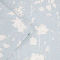 a blue floral wallpaper with white flowers and leaves on the back half of it