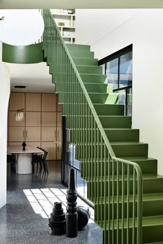 a green stair case next to a table and chairs