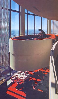 a man is sitting in the middle of a room with large windows and lots of wires