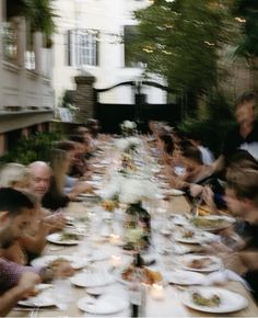 a group of people sitting at a long table with plates and glasses in front of them