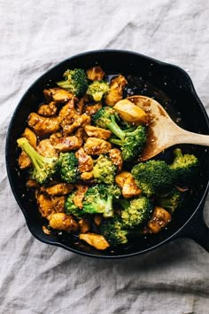 chicken and broccoli in a skillet with a wooden spoon