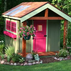 a small garden shed with pink doors and windows