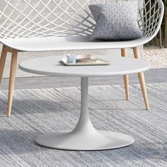 a white table sitting on top of a rug next to a couch and chair with pillows