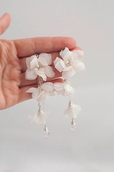 a person is holding some white flowers in their hand and it looks like they have been made out of plastic