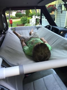 a little boy laying on top of a bed in the back of a truck