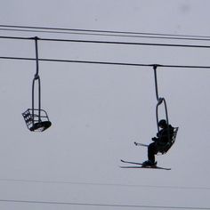 a person riding skis on a lift in the air above power lines and wires