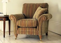 a striped chair sitting next to a table with a lamp on it