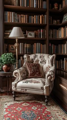 a chair in front of a book shelf with many books on it and a lamp next to it