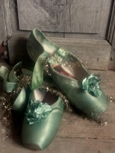 two pairs of green shoes sitting on top of a wooden floor