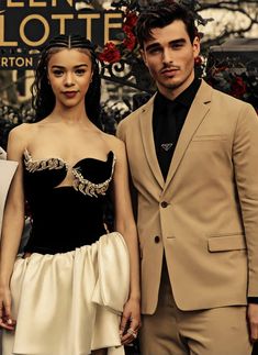 a man and woman standing next to each other in front of a sign that says queen charlotte