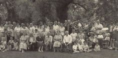 an old black and white photo of a group of people in front of some trees