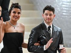 a man and woman standing next to each other in front of some stairs with their hands up