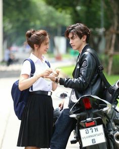 two people standing next to each other on a motorcycle