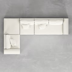 a white couch sitting on top of a cement floor next to pillows and pillow cases