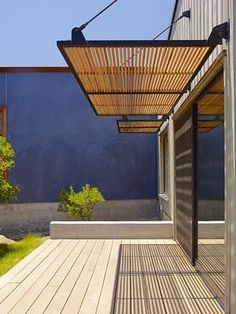 an outdoor covered patio area with wooden flooring and pergolated roof over it