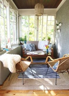 a living room filled with lots of furniture next to a wall covered in plants and windows