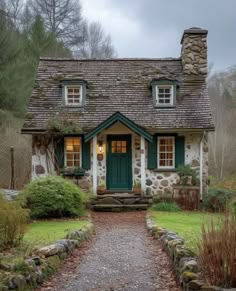 a stone cottage with green shutters and windows on the front door is shown in this photo