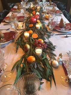 the table is set with candles, fruit and greenery for an elegant dinner party