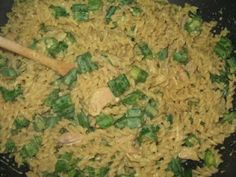 rice and vegetables being cooked in a wok with a wooden spoon on the side