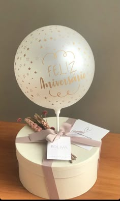 a large white balloon sitting on top of a table next to a card and ribbon