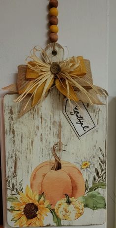 a wooden sign with sunflowers and a pumpkin on it hanging from a wall