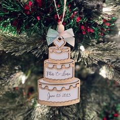 a christmas ornament hanging from a tree with a wedding cake on it's side