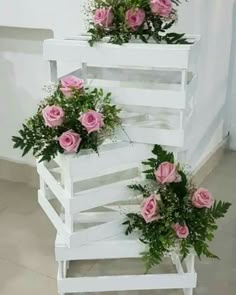 three white planters with pink roses in them on top of each other next to a wall