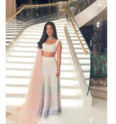 a woman standing in front of some stairs wearing a white and pink dress with sheer cut outs