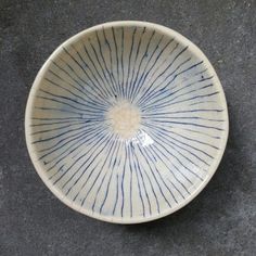 a blue and white bowl sitting on top of a gray floor next to a wall